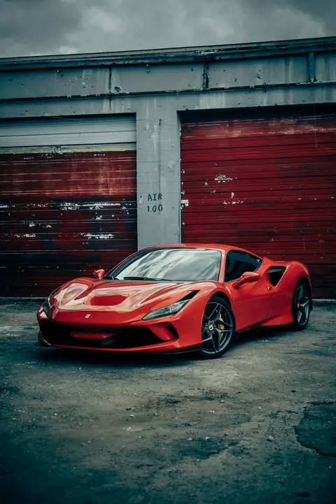 Red Ferrari parked by a red wall